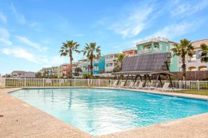 a swimming pool with chairs and palm trees and buildings at IR149 2nd Floor Studio Condo with Gulf View, Shared Pools, Boardwalks in Port Aransas