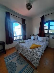 a bedroom with a bed and two windows at Essaouira Beach Hostel in Essaouira