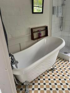 a white bath tub in a bathroom with a tile floor at The Gatehouse in Long Melford