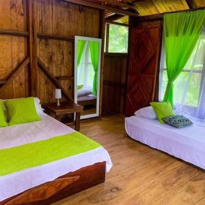 1 dormitorio con 2 camas, sábanas verdes y ventanas en Mama Yeya raíces, en San Cipriano