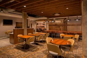 uma sala de jantar com mesas e cadeiras de madeira em TownePlace Suites by Marriott Foley at OWA em Foley