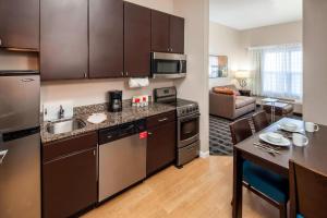 a kitchen with stainless steel appliances and a living room at TownePlace Suites Columbus in Columbus