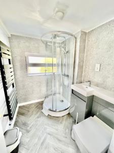 y baño con ducha, aseo y lavamanos. en Bay View Apartment - Trearddur Bay en Trearddur