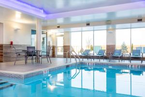 una piscina con sillas y una mesa en un edificio en Fairfield Inn & Suites by Marriott Boston Walpole, en Walpole