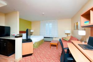 um quarto de hotel com um quarto com uma cama e uma secretária em TownePlace Suites by Marriott Bloomington em Bloomington