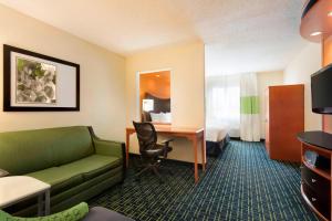 Habitación de hotel con sofá, escritorio y cama en Fairfield Inn & Suites by Marriott Champaign, en Champaign