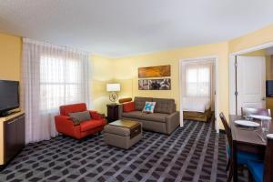 a living room with a couch and chairs and a television at TownePlace Suites Pensacola in Pensacola