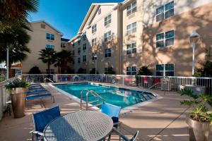 uma piscina com cadeiras e uma mesa e um edifício em TownePlace Suites Pensacola em Pensacola