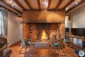 a living room with a brick fireplace with two chairs at Le Logis Bleu in Senantes