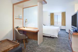 um quarto de hotel com uma cama, uma secretária e uma televisão em Springhill Suites by Marriott Wichita East At Plazzio em Wichita