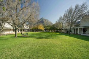 ケープタウンにあるProtea Hotel by Marriott Cape Town Mowbrayの背景の木々と山がある公園