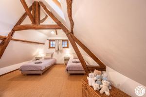 un dormitorio en el ático con 2 camas y animales de peluche en Le Logis Bleu en Senantes