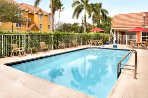 TownePlace Suites Fort Lauderdale West في فورت لاودردال: مسبح مع كراسي ومظلات بجوار منزل