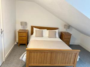 1 dormitorio con 1 cama de madera y 2 mesitas de noche en Douglas Street Apartment, en Nairn
