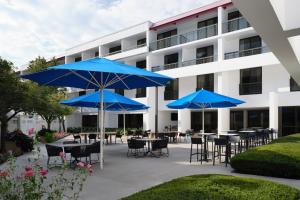 patio ze stołami i niebieskimi parasolami przed budynkiem w obiekcie Marriott Park Ridge w mieście Park Ridge