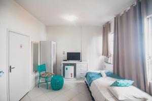 1 dormitorio con 1 cama, 1 silla y TV en Hotel Novo Biarritz Copacabana, en Río de Janeiro