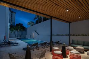 eine Terrasse mit Tischen und Stühlen und einem Pool in der Unterkunft Courtyard by Marriott Santo Domingo in Santo Domingo