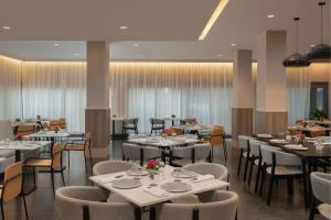 un comedor con mesas y sillas blancas y registradora en Courtyard by Marriott Santo Domingo, en Santo Domingo