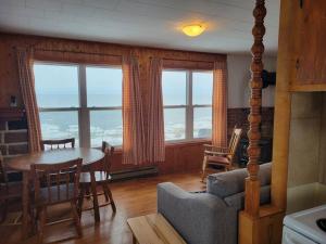 a living room with a table and chairs and windows at Le petit chalet de pierres in Sainte-Luce-sur-Mer