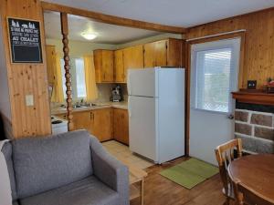 une cuisine avec un réfrigérateur blanc et une table dans l'établissement Le petit chalet de pierres, à Sainte-Luce-sur-Mer 10 autres photos