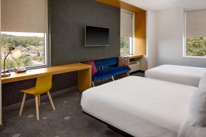 a hotel room with a bed and a desk and a bed and a desk at Aloft Chapel Hill in Chapel Hill