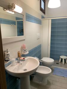 ein Badezimmer mit einem Waschbecken, einem WC und einem Spiegel in der Unterkunft B&B Giostemar - Playa Grande in Scicli