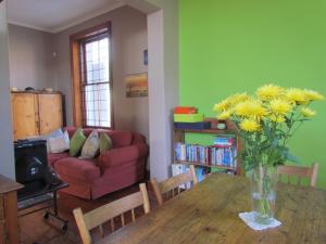 um vaso de flores amarelas numa mesa de madeira numa sala de estar em Victorian Woodstock na Cidade do Cabo