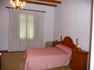 1 dormitorio con cama rosa y ventana en Casa del Priorat "Ca La María", en Marçà