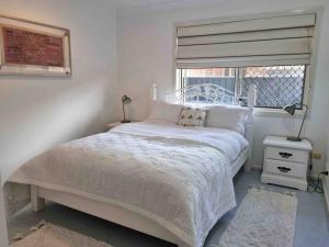 a bedroom with a white bed and a window at Charming 4 Bedroom Waterfront Home W/ Pool Near Casino in Gold Coast
