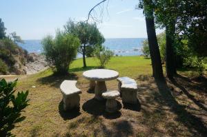 a stone table and stools sitting next to the ocean at La Villa Case Marine in Sari Solenzara