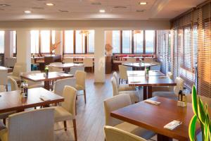 een restaurant met houten tafels, stoelen en ramen bij Marriott’s Club Son Antem in Llucmajor