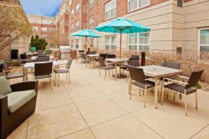 een patio met tafels en stoelen en blauwe parasols bij Residence Inn Indianapolis Carmel in Carmel