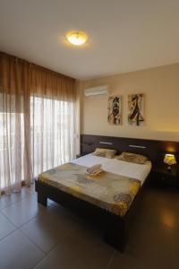 een slaapkamer met een groot bed voor een raam bij Indigo luxury apartments in Olympiakí Aktí