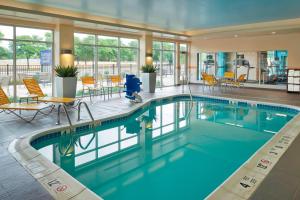 uma piscina no átrio do hotel com cadeiras e mesas em Fairfield by Marriott Niagara Falls em Niagara Falls