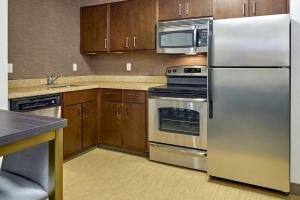 una cocina con electrodomésticos de acero inoxidable y armarios de madera en Residence Inn Eugene Springfield, en Eugene