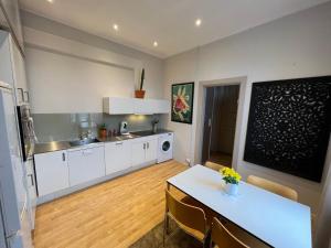 a kitchen with white cabinets and a table and a dining room at Fredrikstad Cicignon, peaceful but central with garden, parking and long stay facilities in Fredrikstad