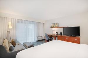 a hotel room with a bed and a desk and a television at Courtyard by Marriott Birmingham Homewood in Birmingham