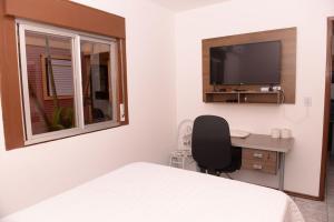 a bedroom with a bed and a desk and a television at Apto completo e aconchegante em Santa Rosa RS in Santa Rosa