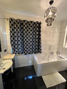 y baño con bañera, lavabo y lámpara de araña. en Apartamenty Południe BB, en Bielsko-Biala