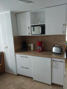 a kitchen with white cabinets and a microwave at Ferienwohnung Glasperlenfloh in Ilmenau