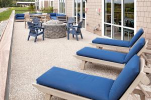 a group of blue chairs and tables on a patio at TownePlace Suites by Marriott Wareham Buzzards Bay in Wareham