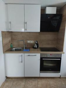 a kitchen with white cabinets and a sink at Ferienwohnung Glasperlenfloh in Ilmenau +5 photos
