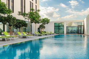 une piscine avec des chaises et un bâtiment dans l'établissement Element Me'aisam, Dubai, à Dubaï