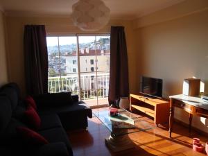 a living room with a couch and a large window at Excelente T3 Duplex Funchal in Funchal