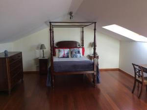 um quarto com uma cama de dossel e piso em madeira em Excelente T3 Duplex Funchal no Funchal