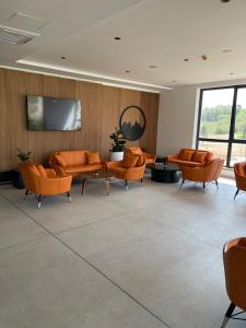 a waiting room with orange chairs and a flat screen tv at Apartman Bella Fruške Residences in Vrdnik