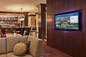 a living room with a couch with a television on a wall at Courtyard by Marriott Odessa in Odessa