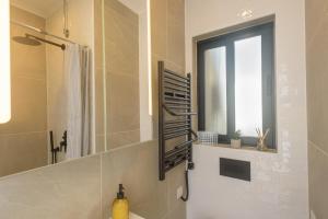 Un baño con lavabo, espejo y ventana. en Sarah's Penthouse in Sliema, en Sliema