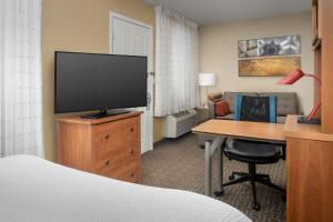 a hotel room with a bed and a desk with a television at TownePlace Suites by Marriott Portland Hillsboro in Hillsboro