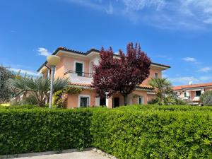 a house with a hedge in front of a building at Villa I Giardini del Conero con ombrellone in spiaggia in Porto Recanati